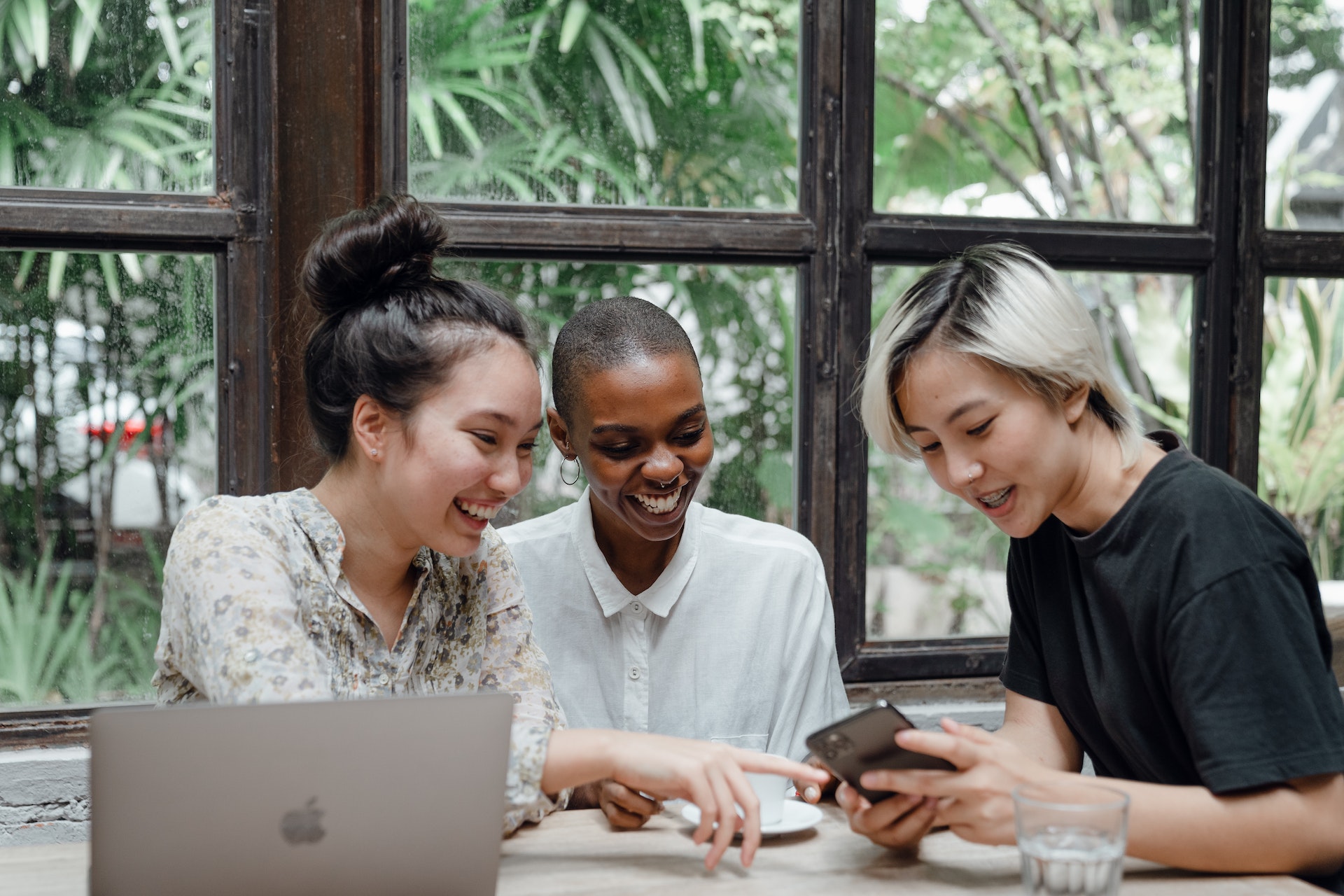 Three marketing professionals laughing and pointing at a phone 