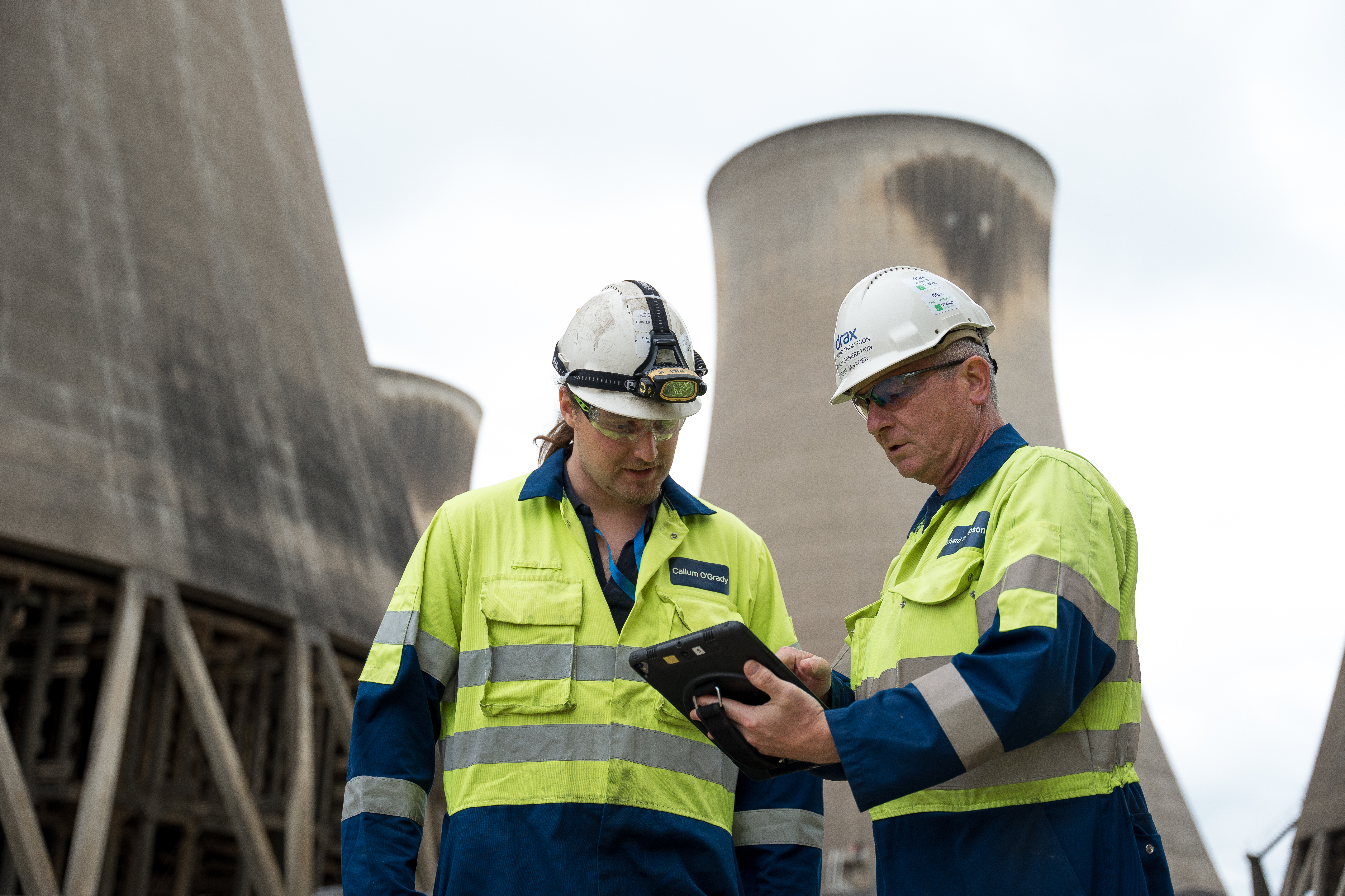 2 engineers outside a power station looking at a digital tablet