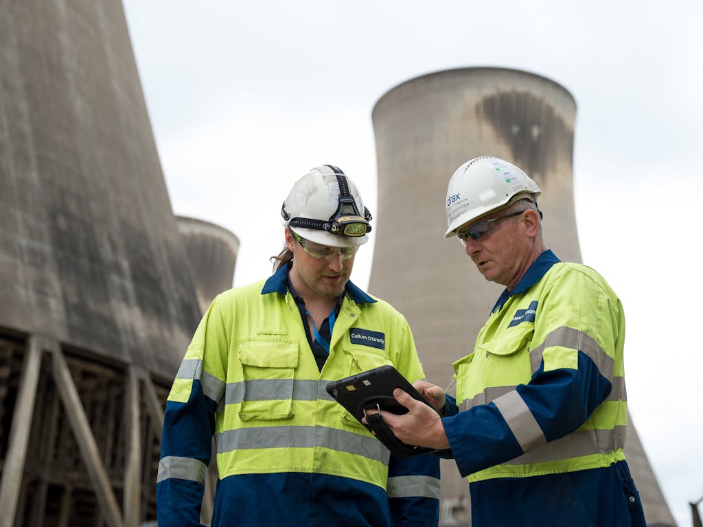 2 engineers outside a power station looking at a digital tablet