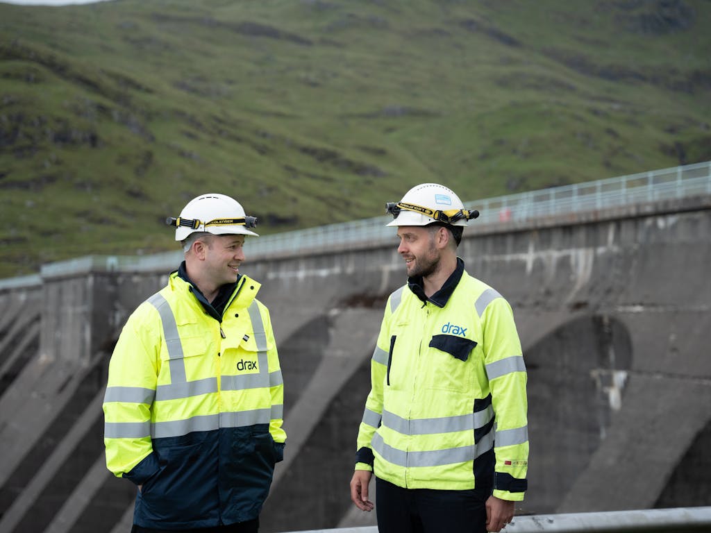2 engineers standing in front of a dam