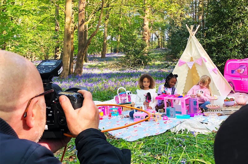 photographer takes picture of 3 young girls having a Barbie tea party in a bluebell covered woodland