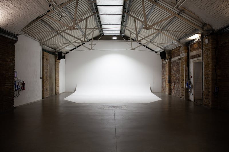 Small photography studio with a white cove wall, and railway arch ceiling