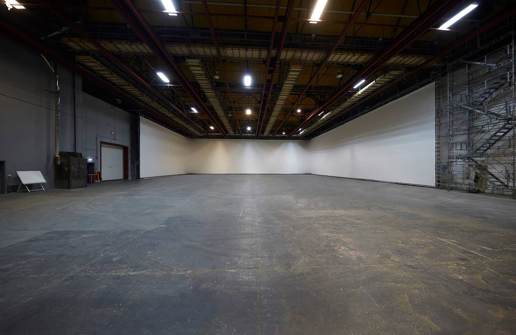 Large empty grey warehouse studio space for filming.