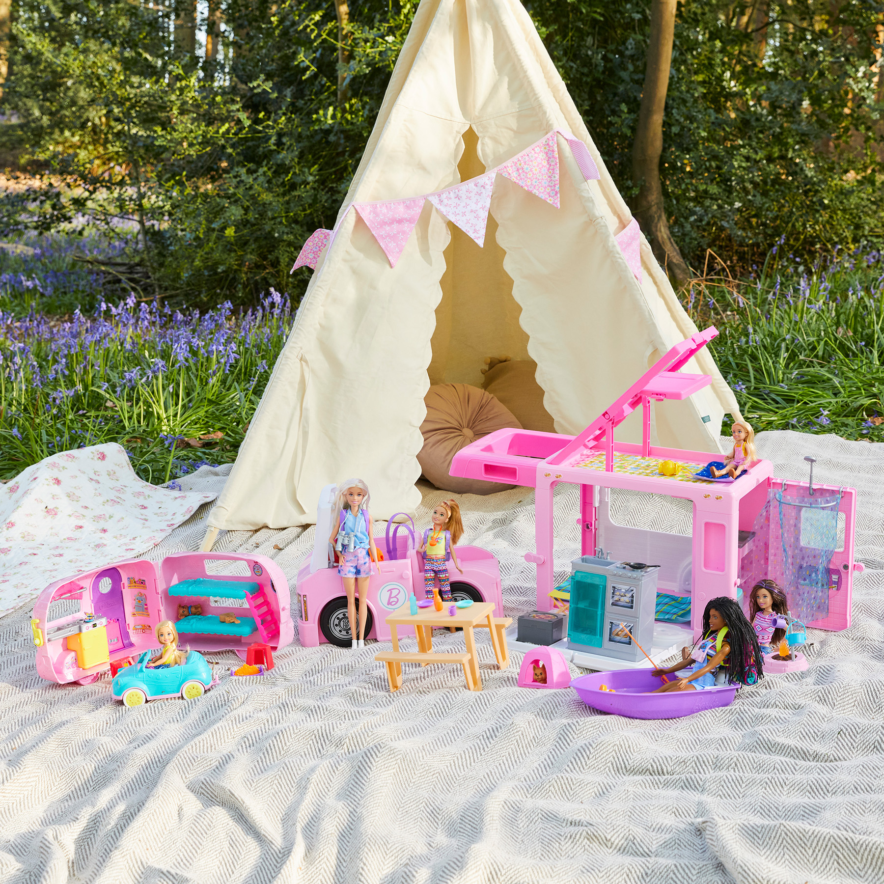 Barbie toys set up on blankets in a woodland picnic