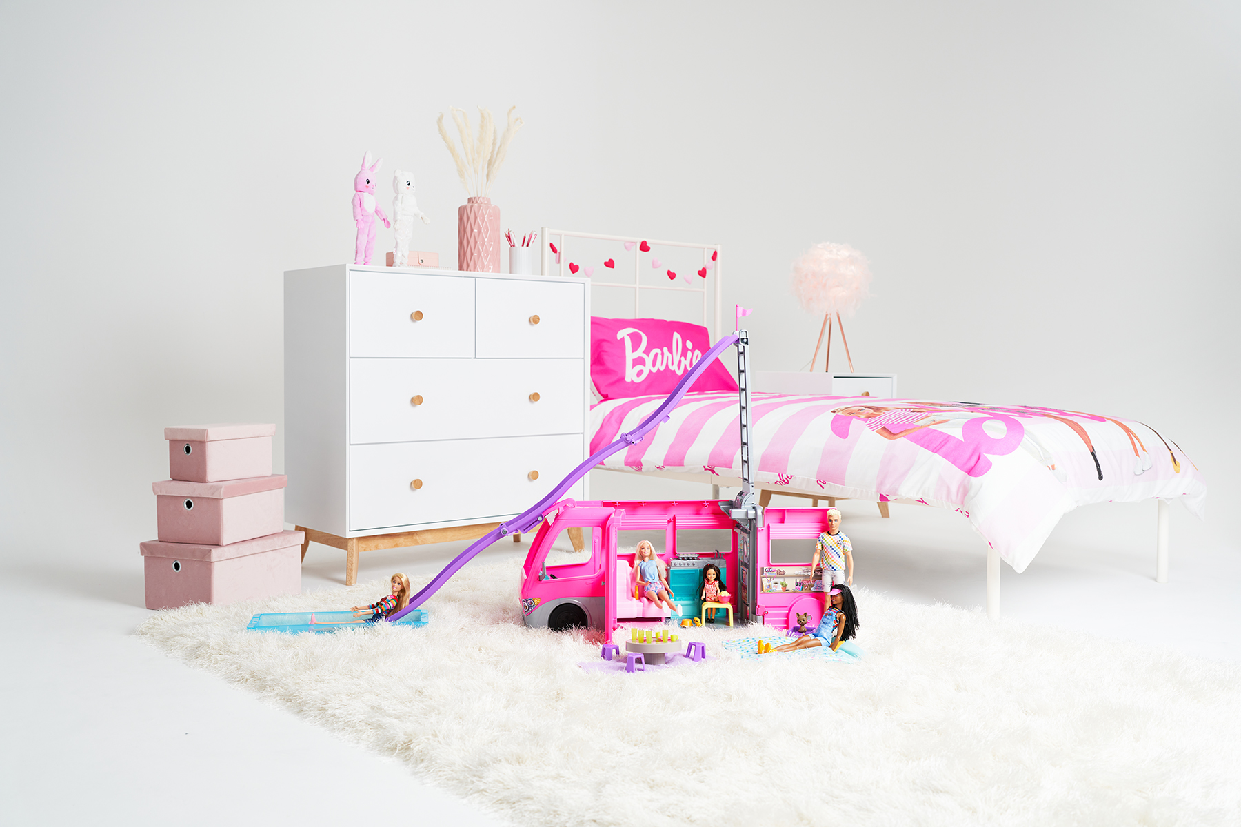 A barbie bedroom set and toys in a white photography studio