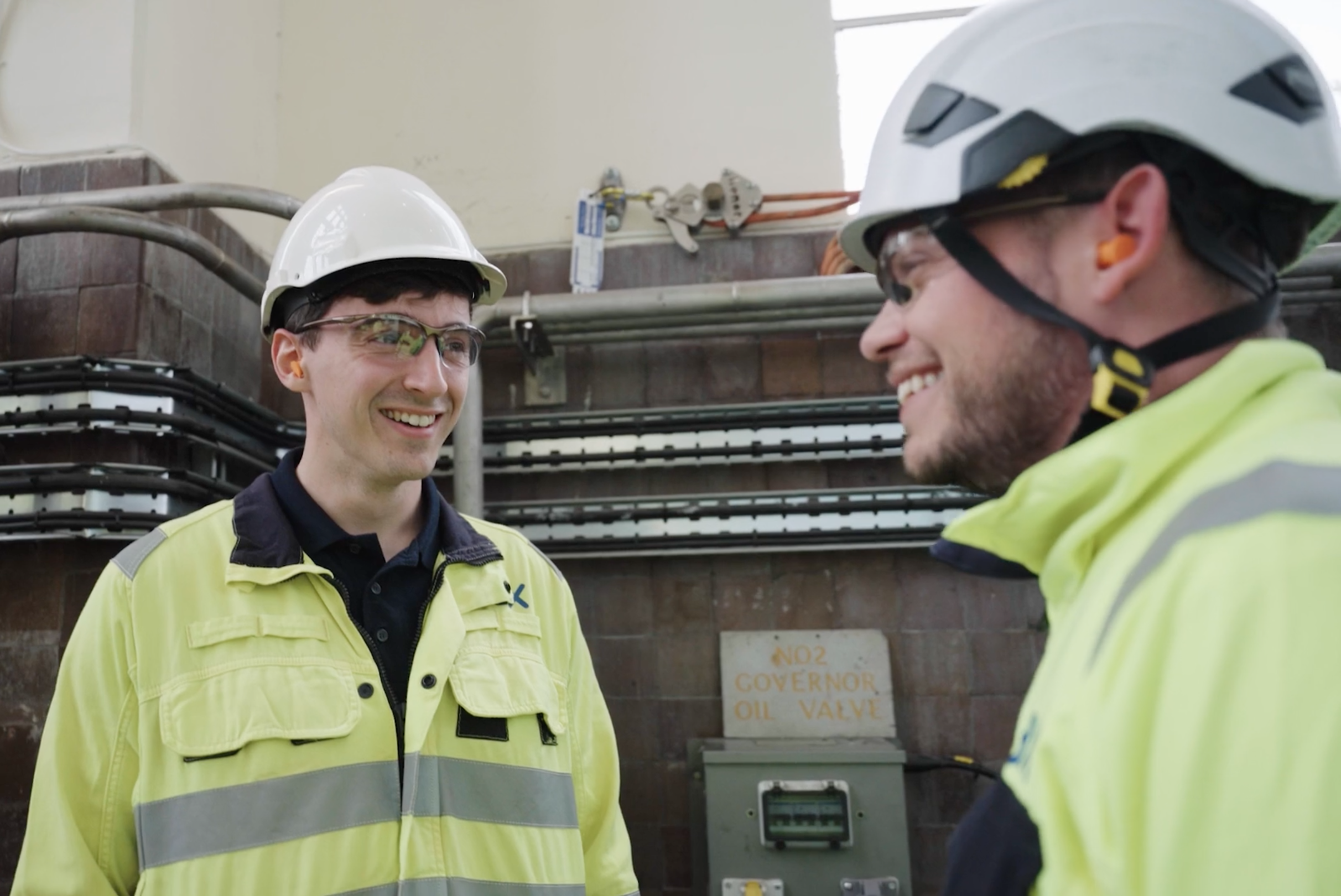 Two Engineers dressed in high-vis talking and smiling