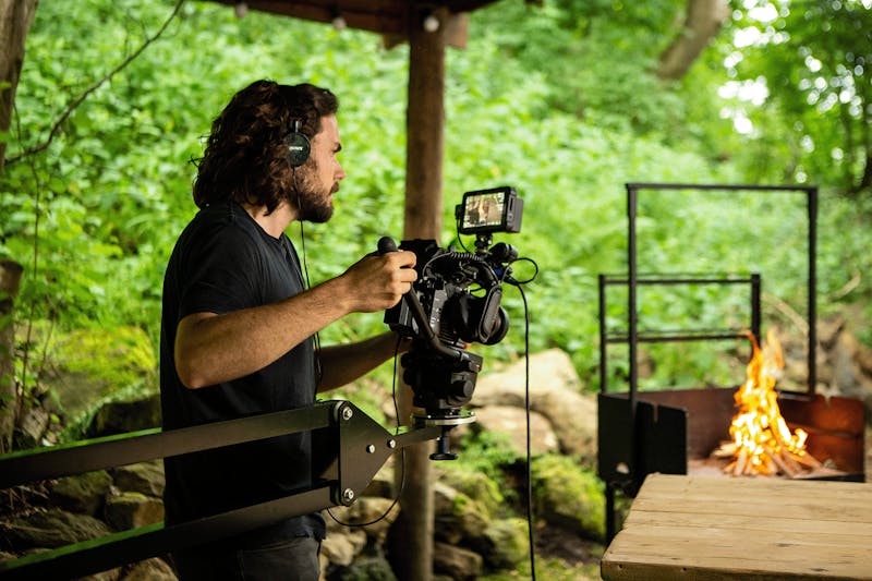 Behind the camera lens, a camera man is filming an outdoor fire
