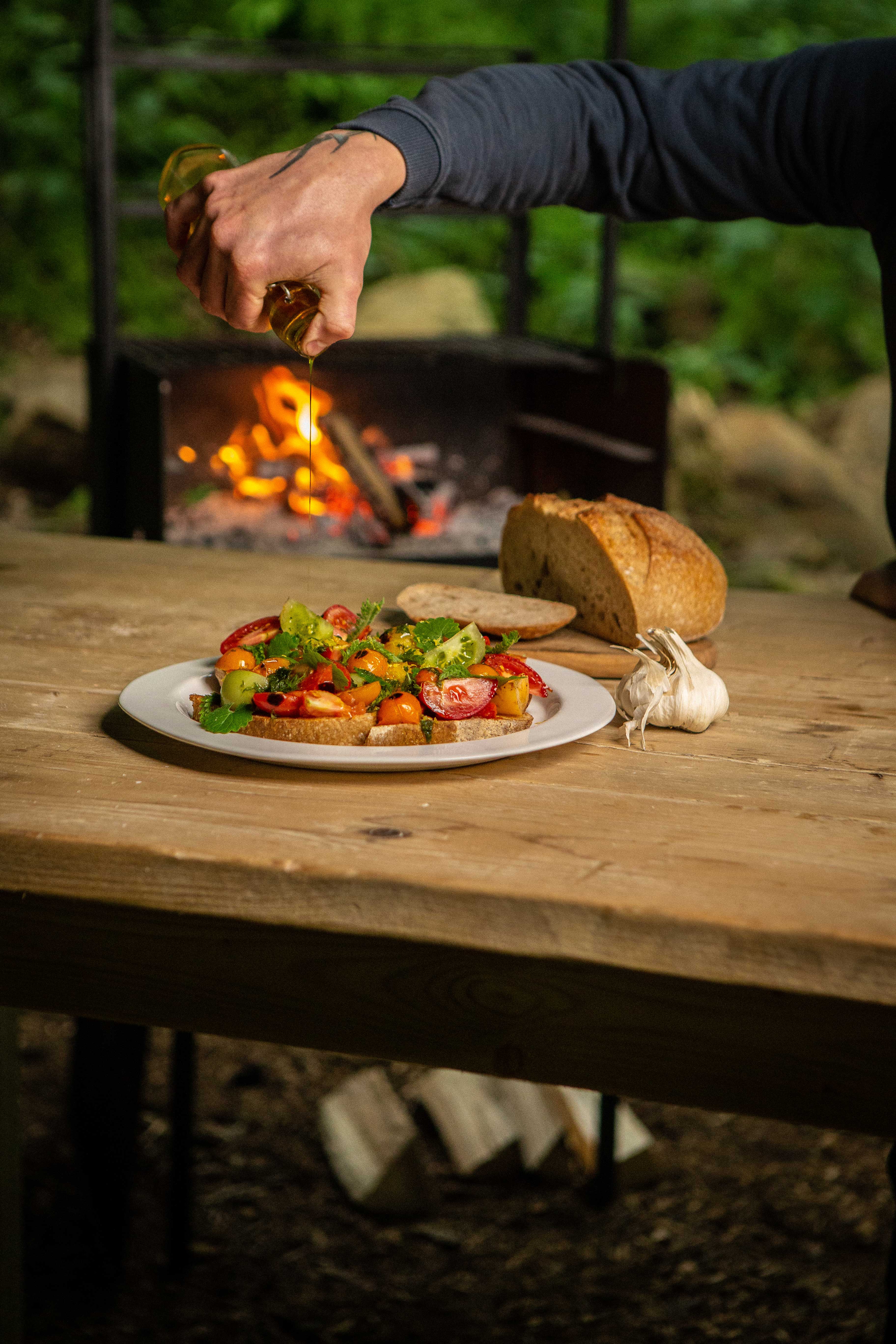 Food photography, fresh heritage tomato bruschetta and freshly baked sourdough in front of an outdoor fire
