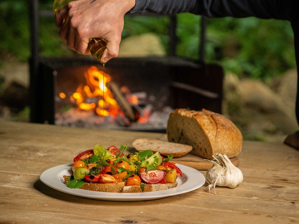 Food photography, fresh heritage tomato bruschetta and freshly baked sourdough in front of an outdoor fire