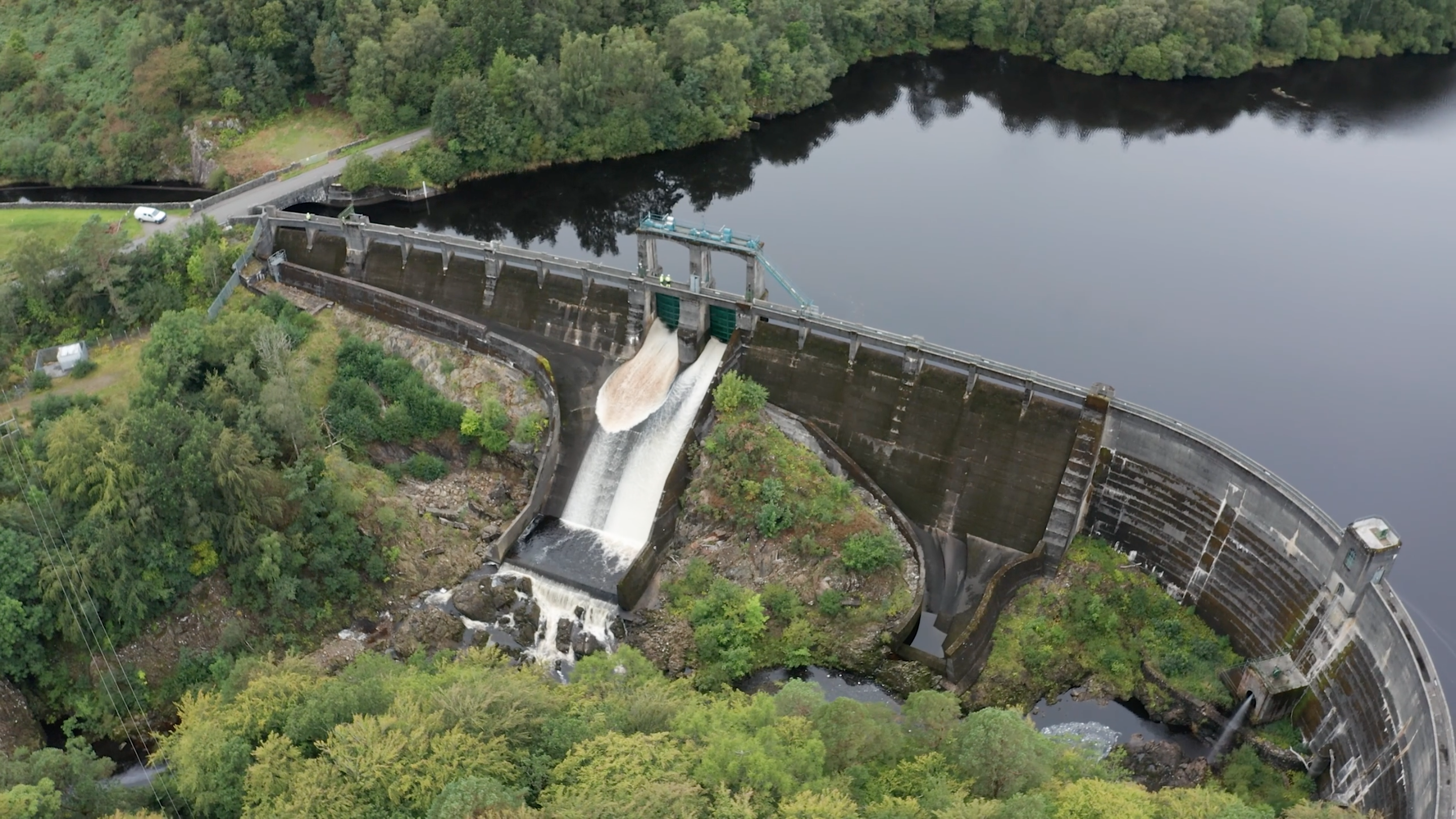 Aerial drone photo of water rushing through gates of a hydro-power damn in Scotland