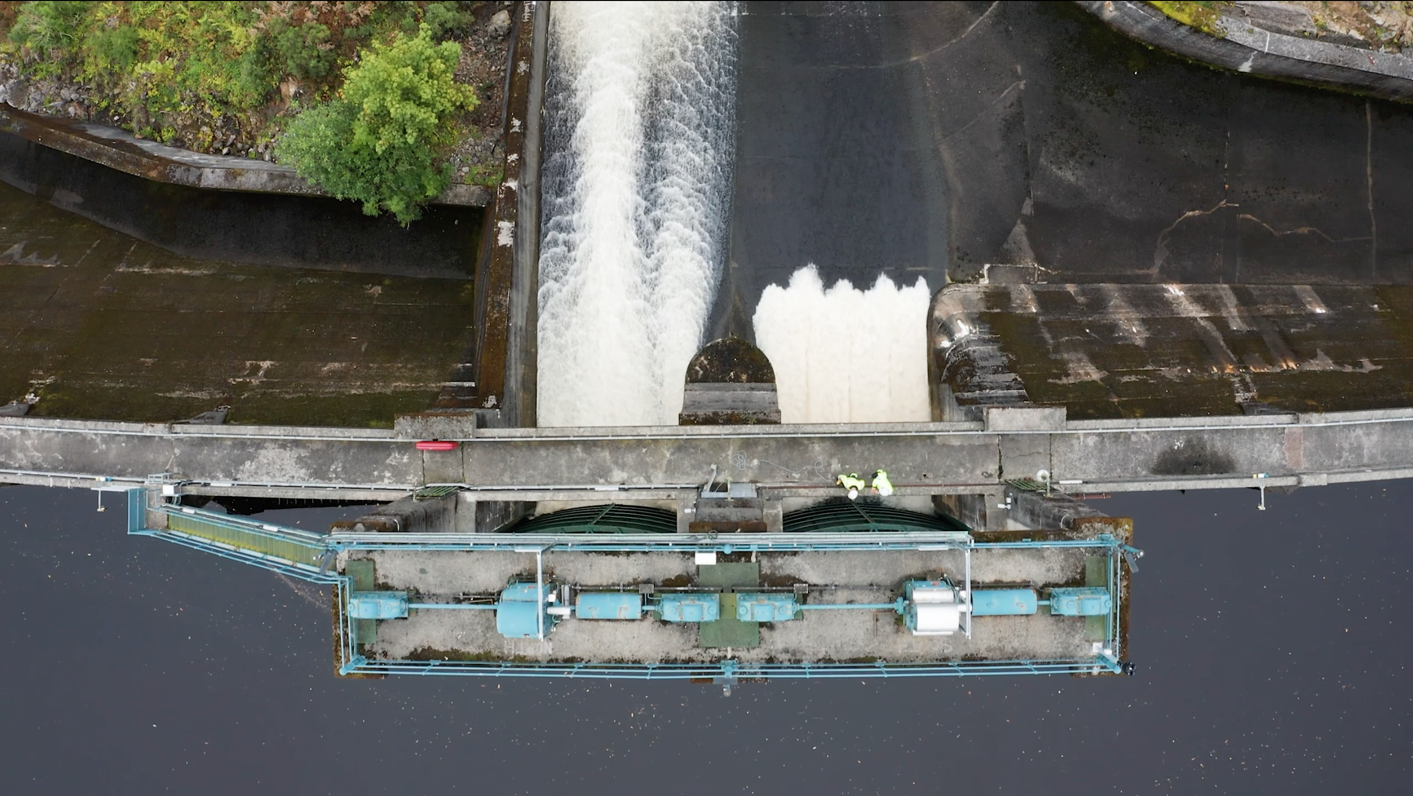 Aerial drone photo of water rushing through gates of a hydro-power damn in Scotland