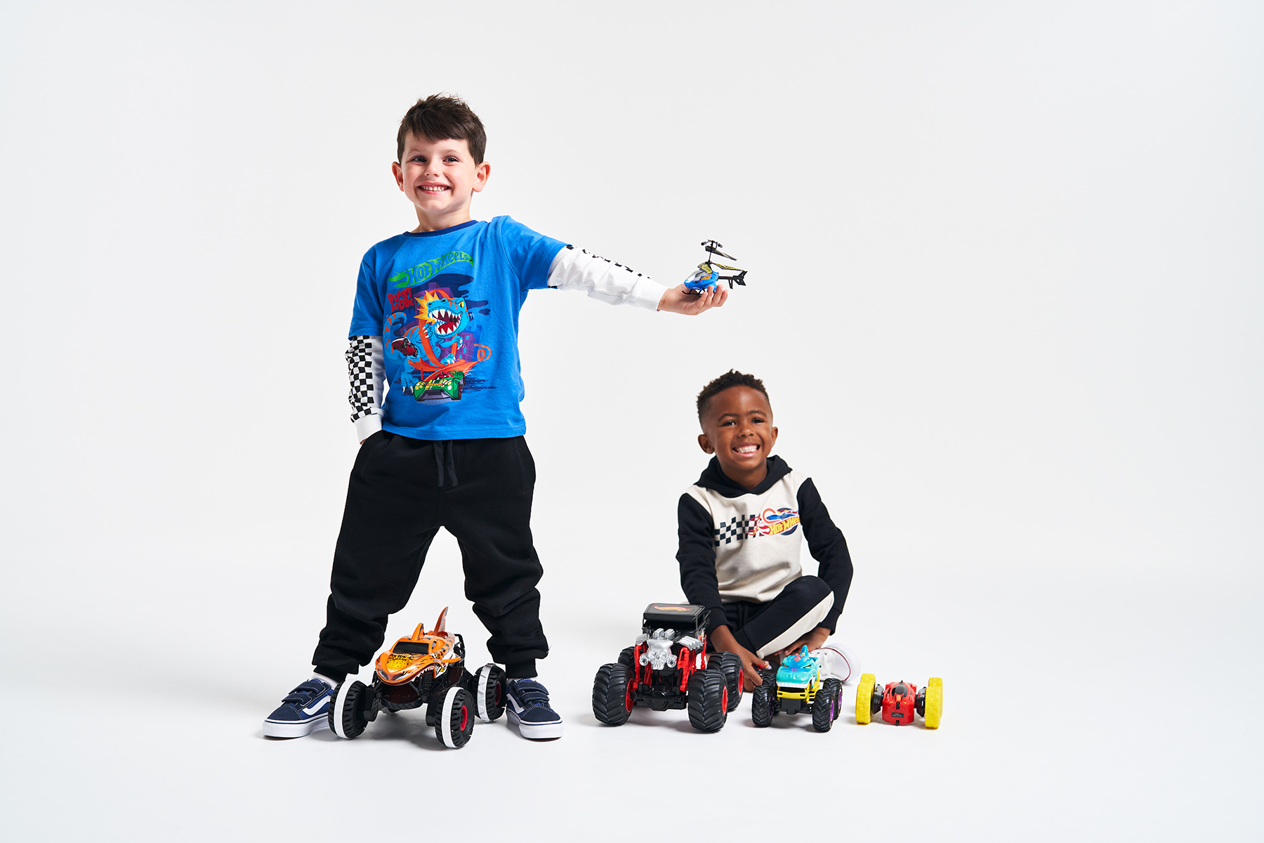 Two young boys smiling with Hot Wheels remote controlled toys around them