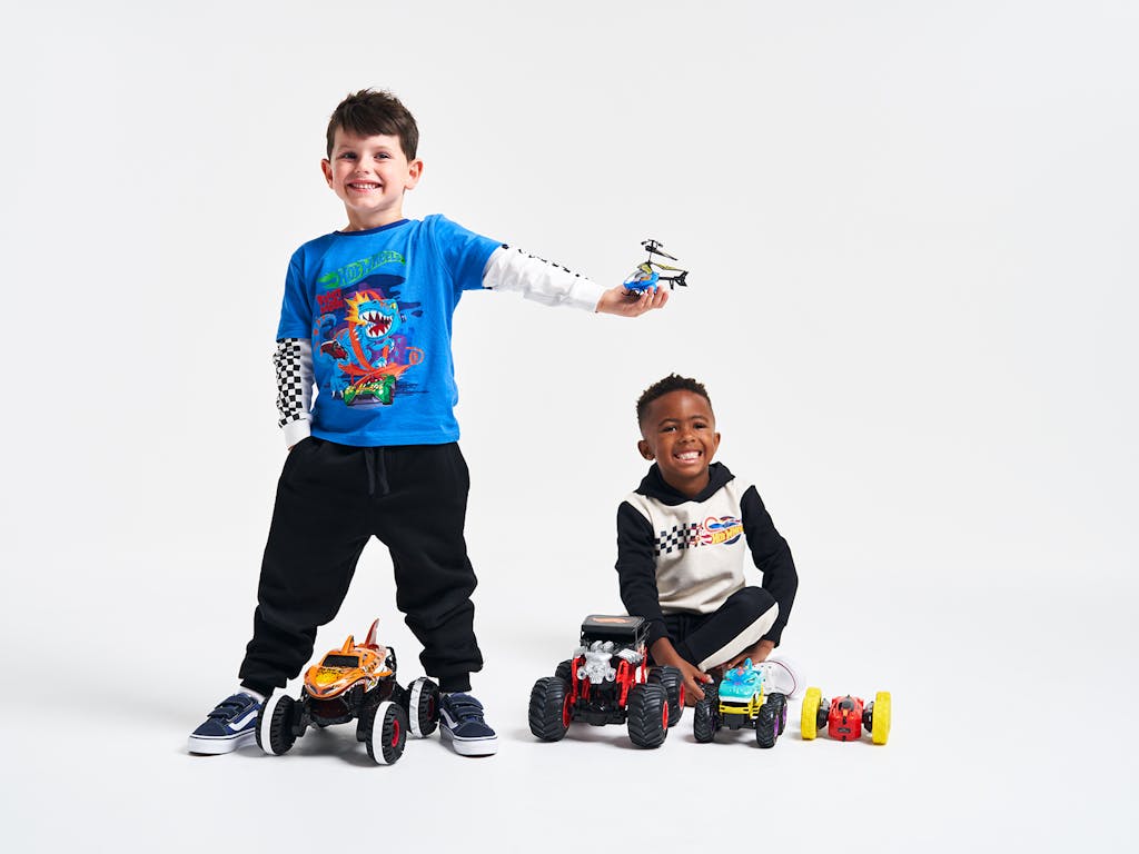 Two young boys smiling with Hot Wheels remote controlled toys around them