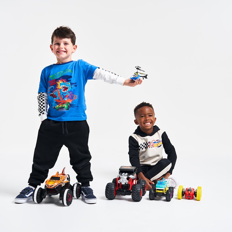 Two young boys smiling with Hot Wheels remote controlled toys around them
