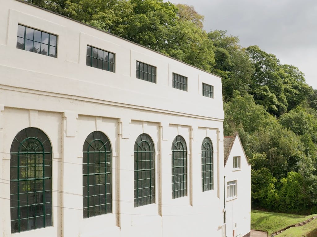 Large, bright, white, art deco style building surrounded by green trees