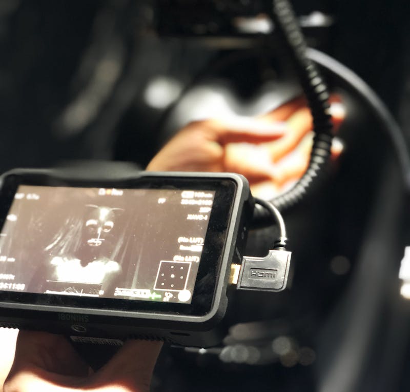 Video camera monitor showing a figure dressed in a black catsuit with mask