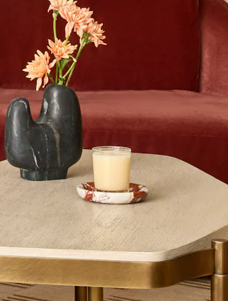 White candle with a vase with a few pastel orange flowers