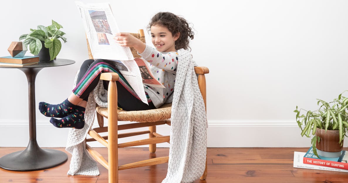 Child sitting on a chair with a throw blanket