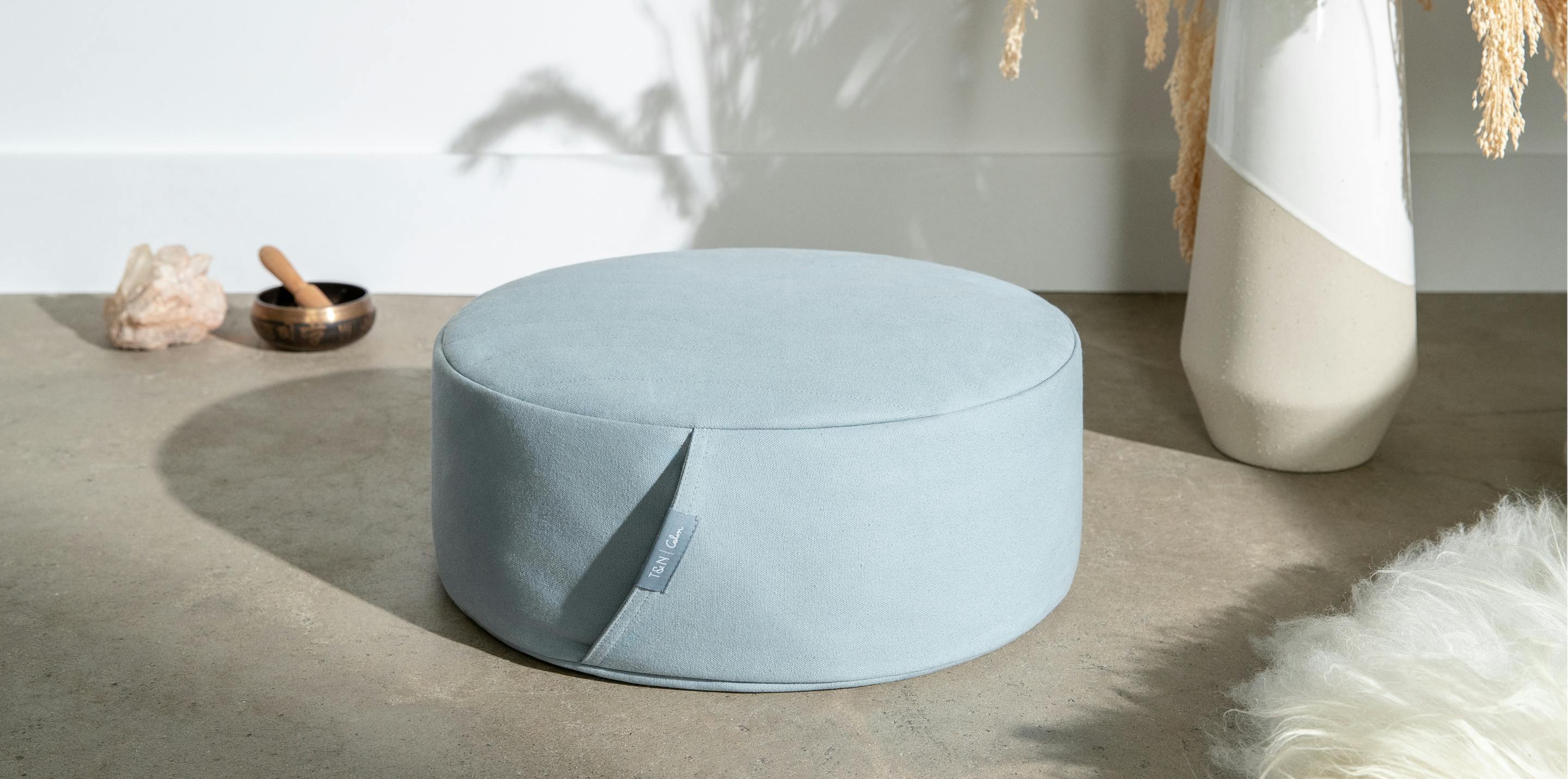 Meditation Cushion on a concrete floor with minimal room decorations.
