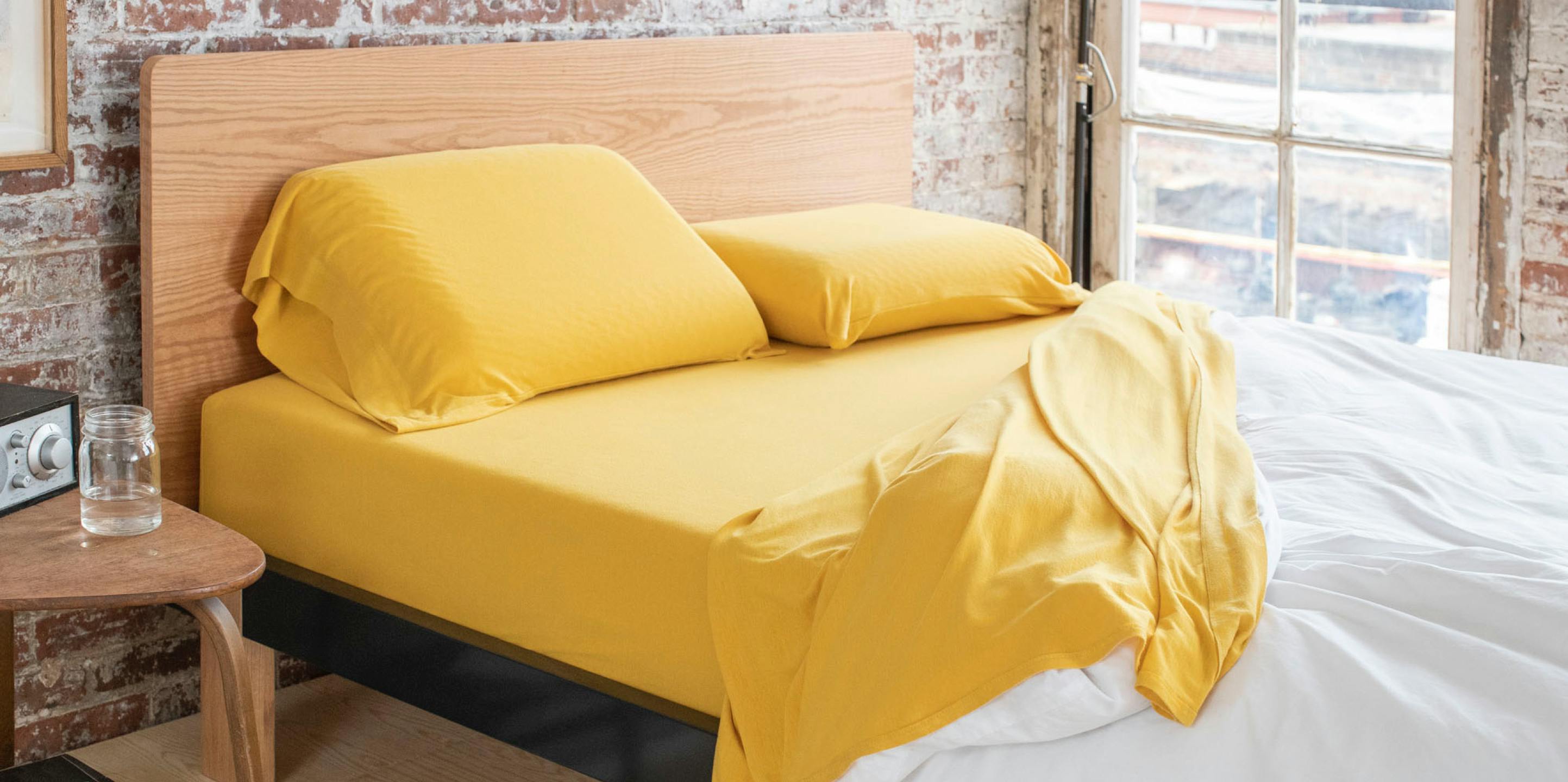 Tuft & Needle bed with marigold jersey sheets in a bedroom