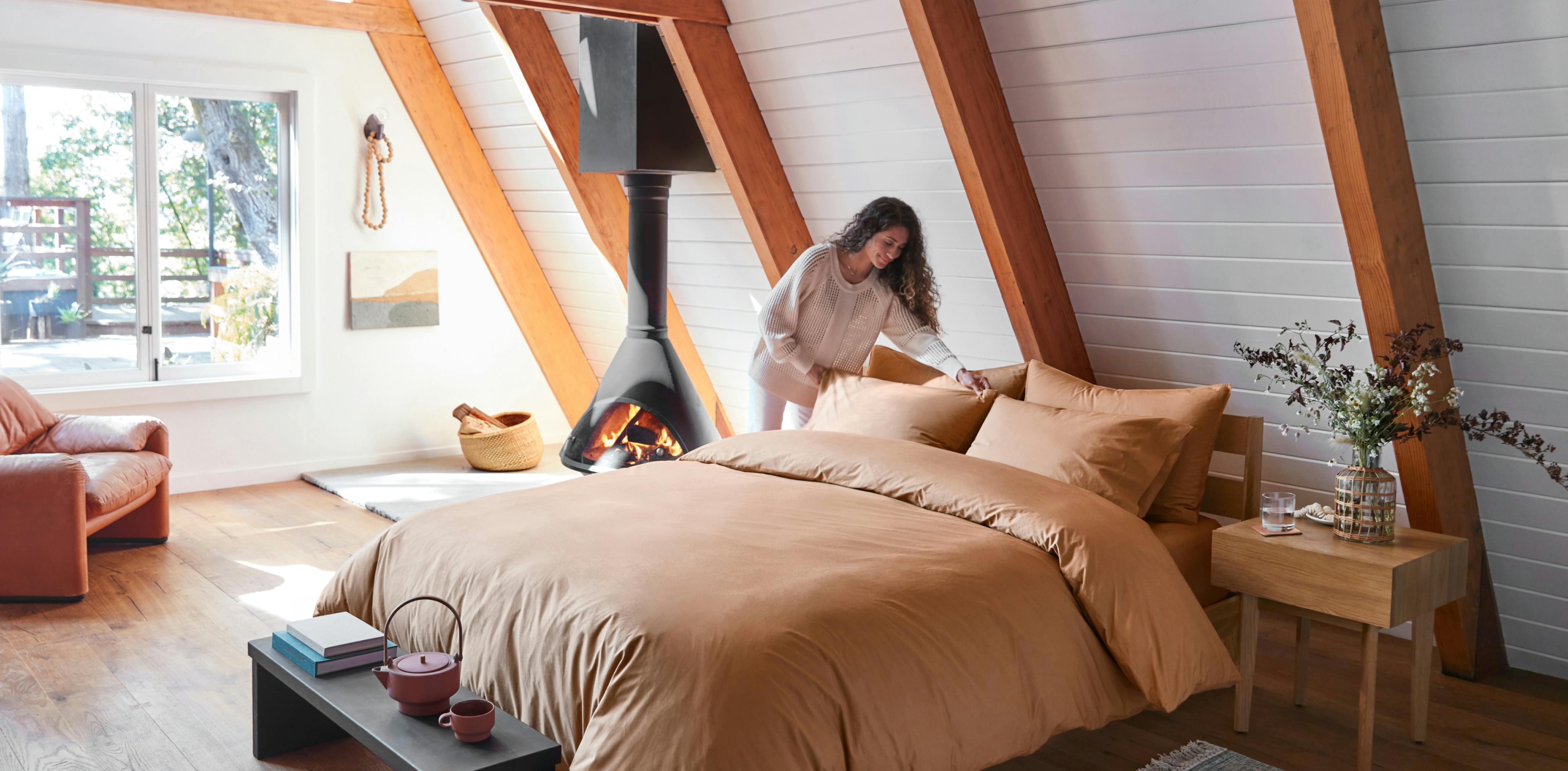 Woman making bed using Percale Sheets and Duvet in Canyon color.