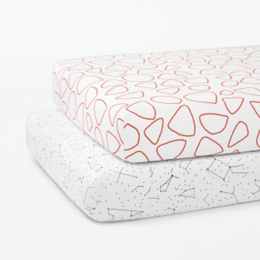 Two crib mattresses stacked on top of one another, fitted with our Pebble and Constellation patterned Crib Sheets