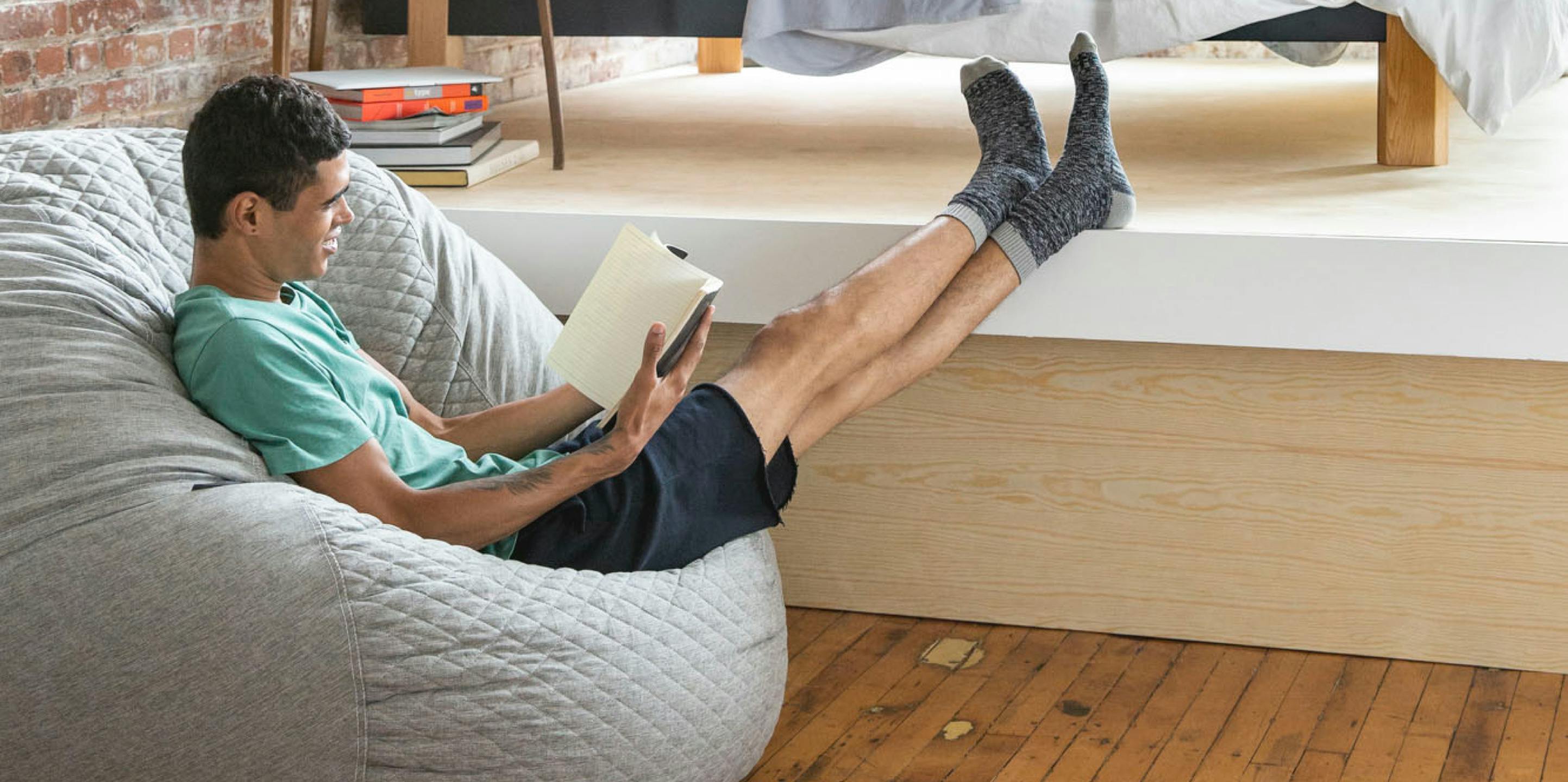 A man sitting on a Pouch reading a book
