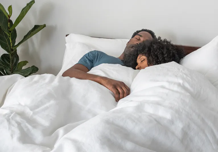 A couple sleeps on a bed.