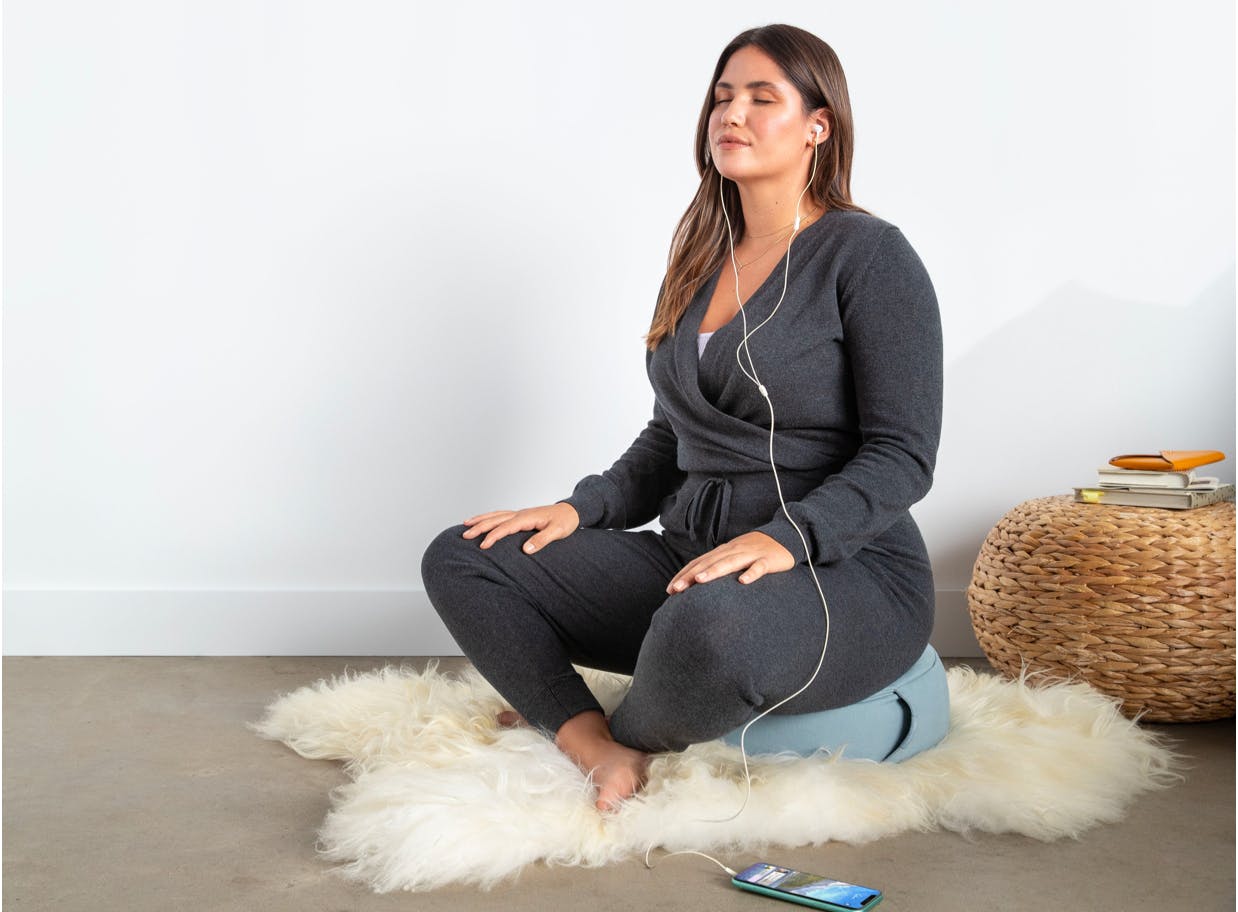 Woman sitting on the Meditation Cushion.