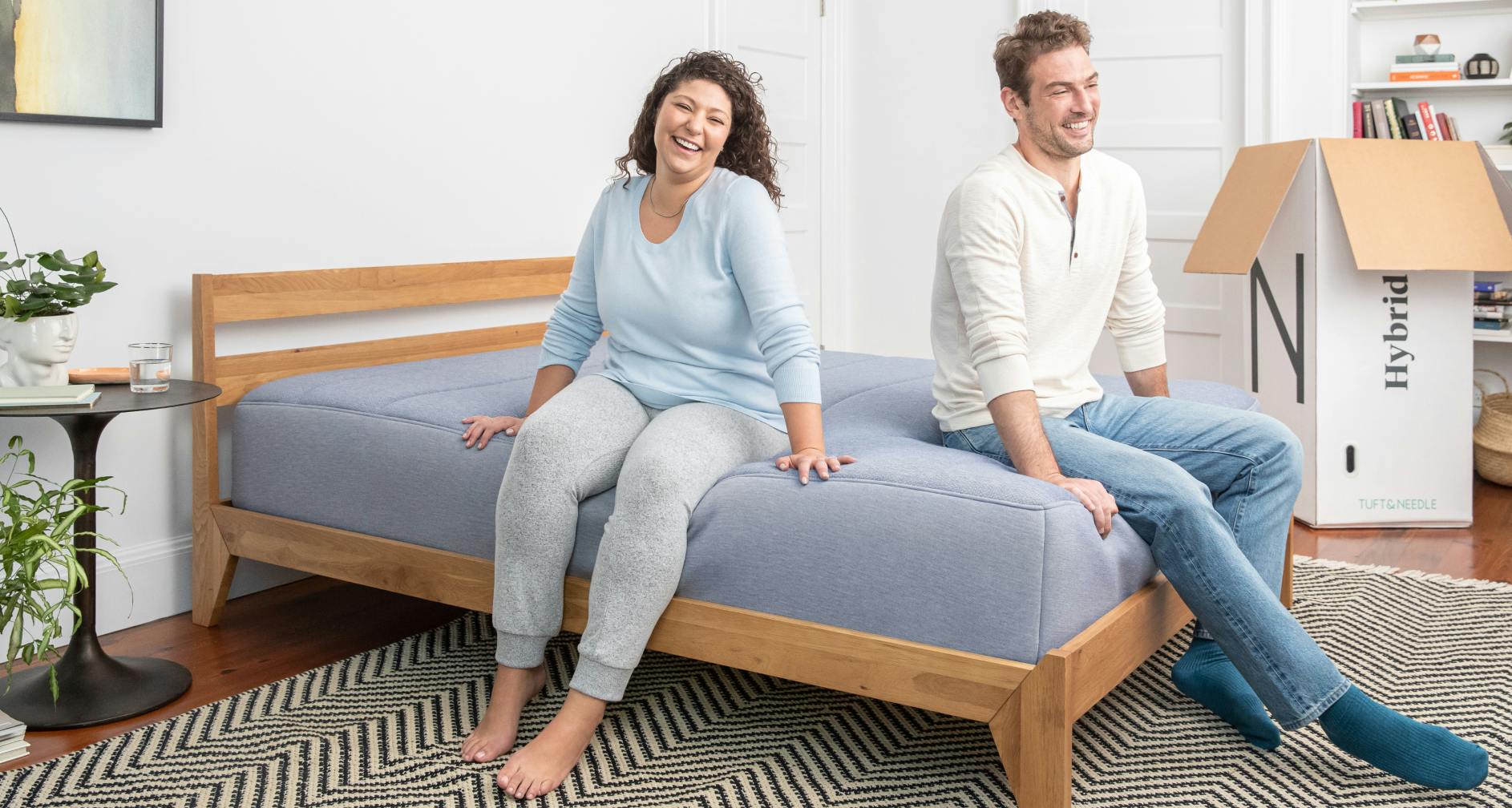 Couple sitting on their new wood frame and Hybrid mattress