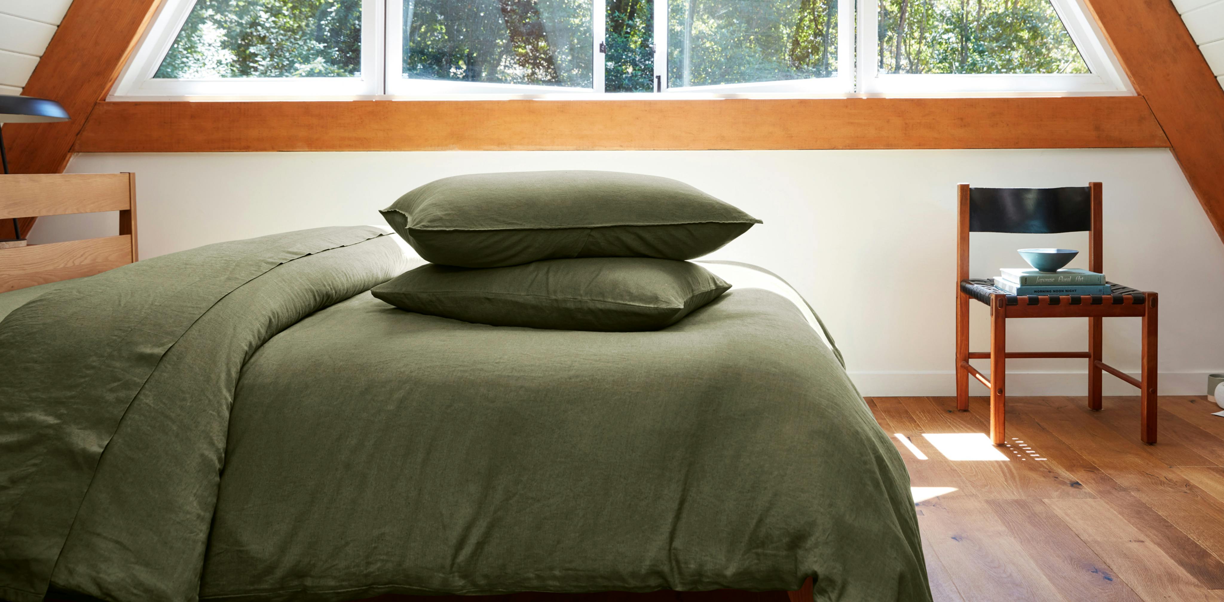 Two Linen Shams on pillows on top of made bed in Moss color.