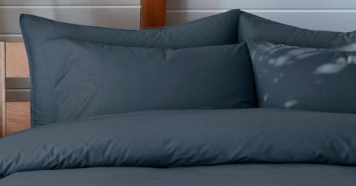 Percale Sheets, Pillowcases, and Duvet on made bed in Slate color. 