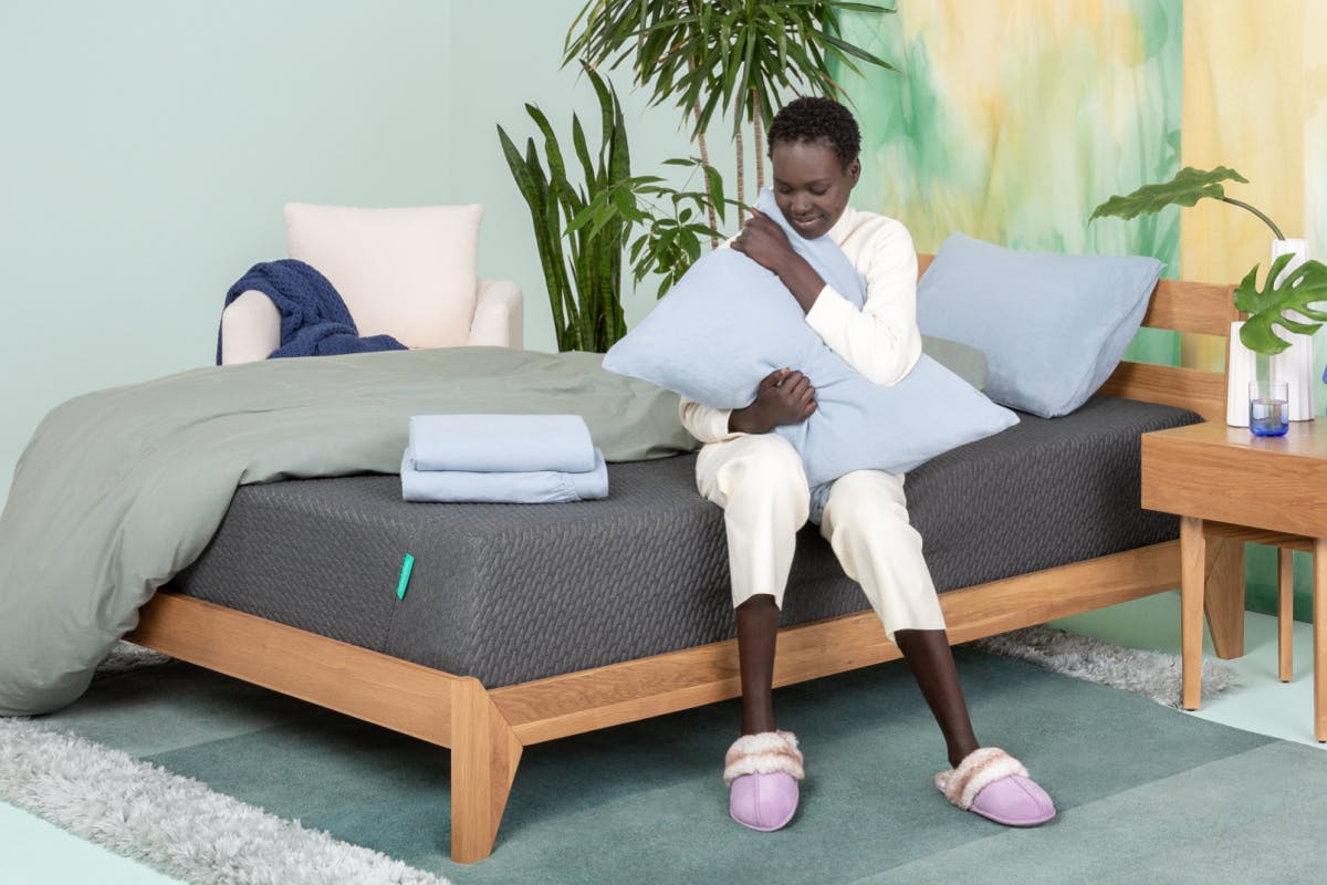 Woman hugs a pillow on her Tuft & Needle bed.