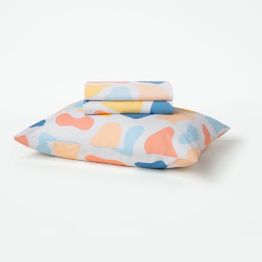 Our Palette patterned toddler sheet set folded sitting on top of a pillow