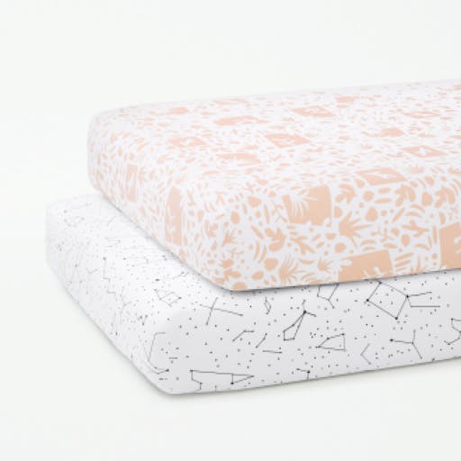 Two crib mattresses stacked on top of one another, fitted with our Flora and Constellation patterned Crib Sheets