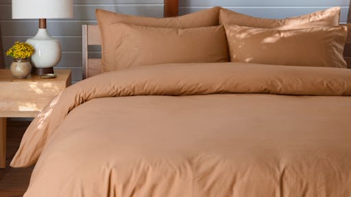 Percale Sheet and Duvet on made bed in Canyon color. 