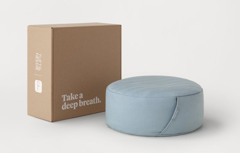 Meditation cushion next to the shipping box which says "Take a deep breath."