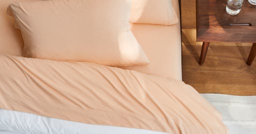 Organic Jersey Sheets on made bed in Melon color.