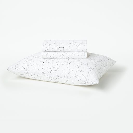 Our Constellation patterned toddler sheet set folded sitting on top of a pillow