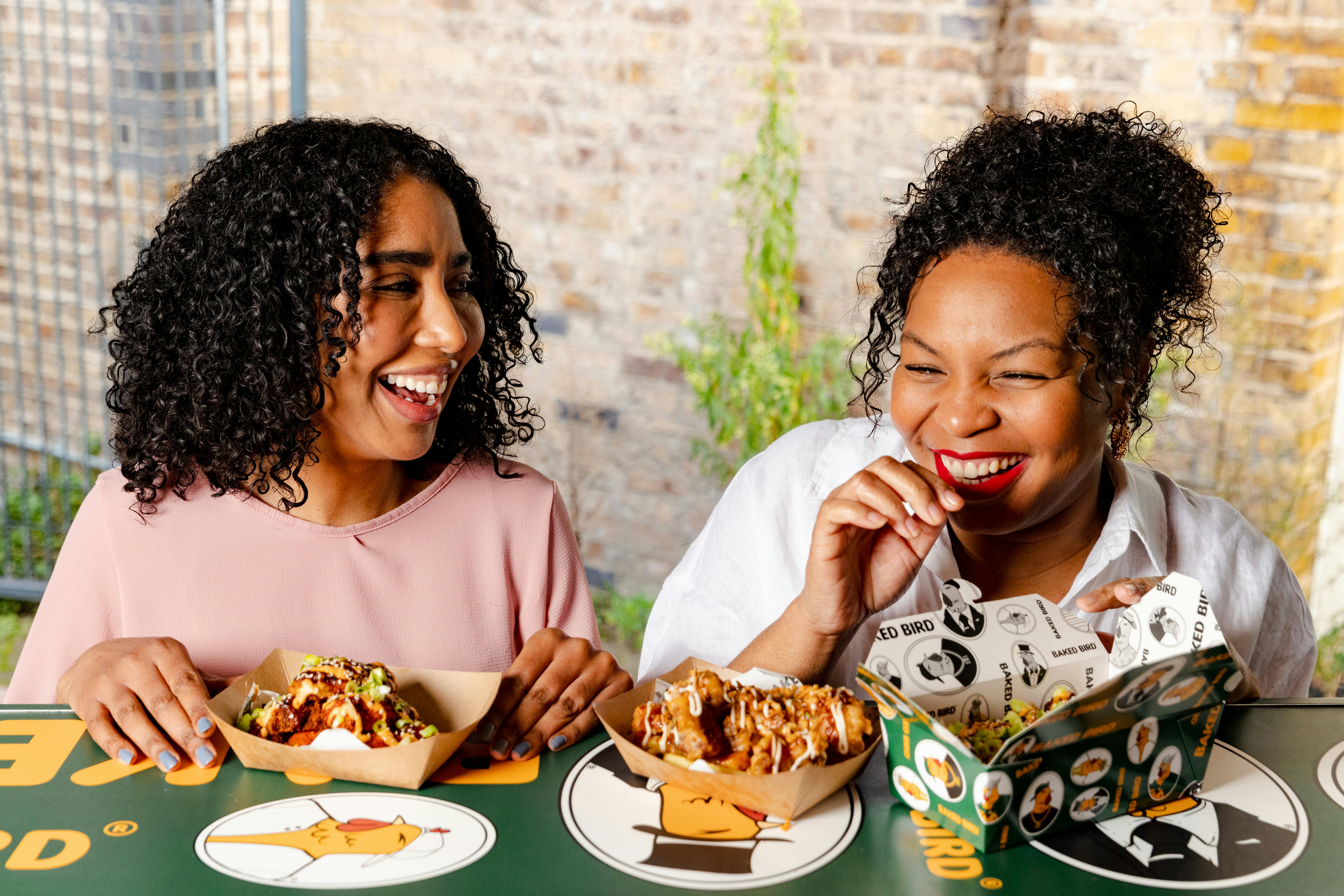 Two colleagues laughing and eating food at a food truck