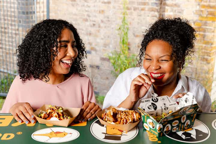 Two colleagues laughing and eating food at a food truck