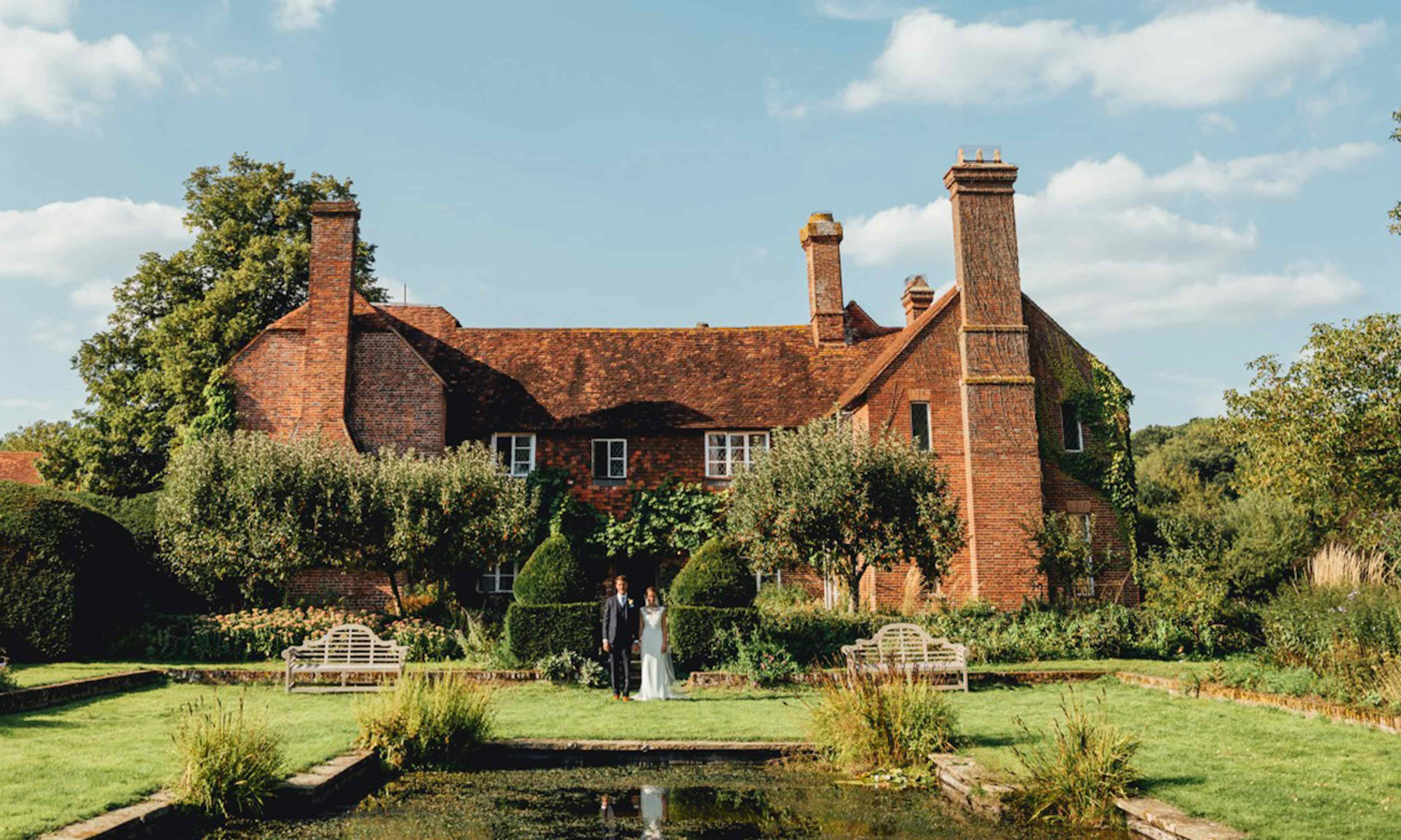 wedding couple in front of old estate with pond