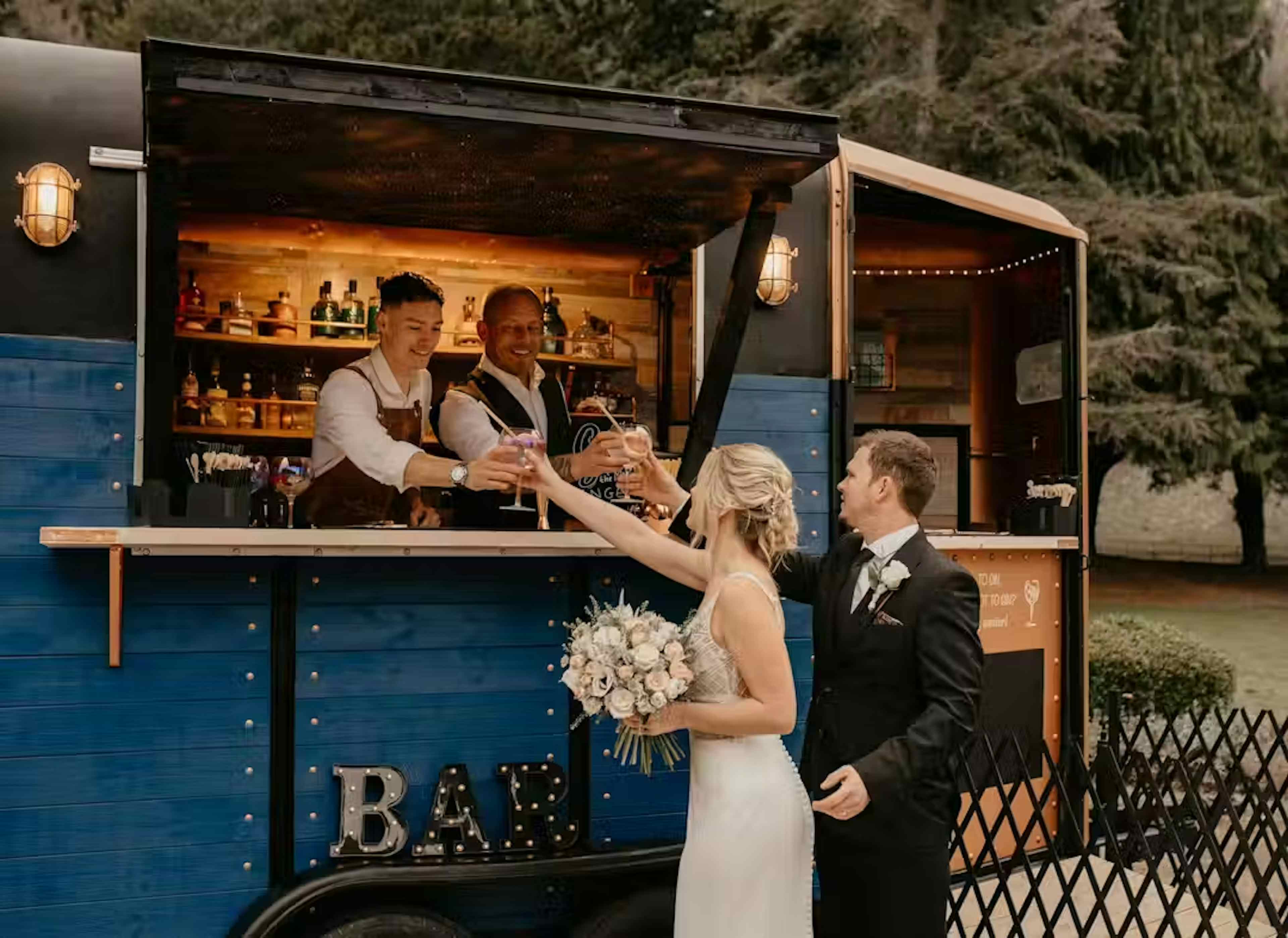 wedding couple grabbing drinks from horsebox bar