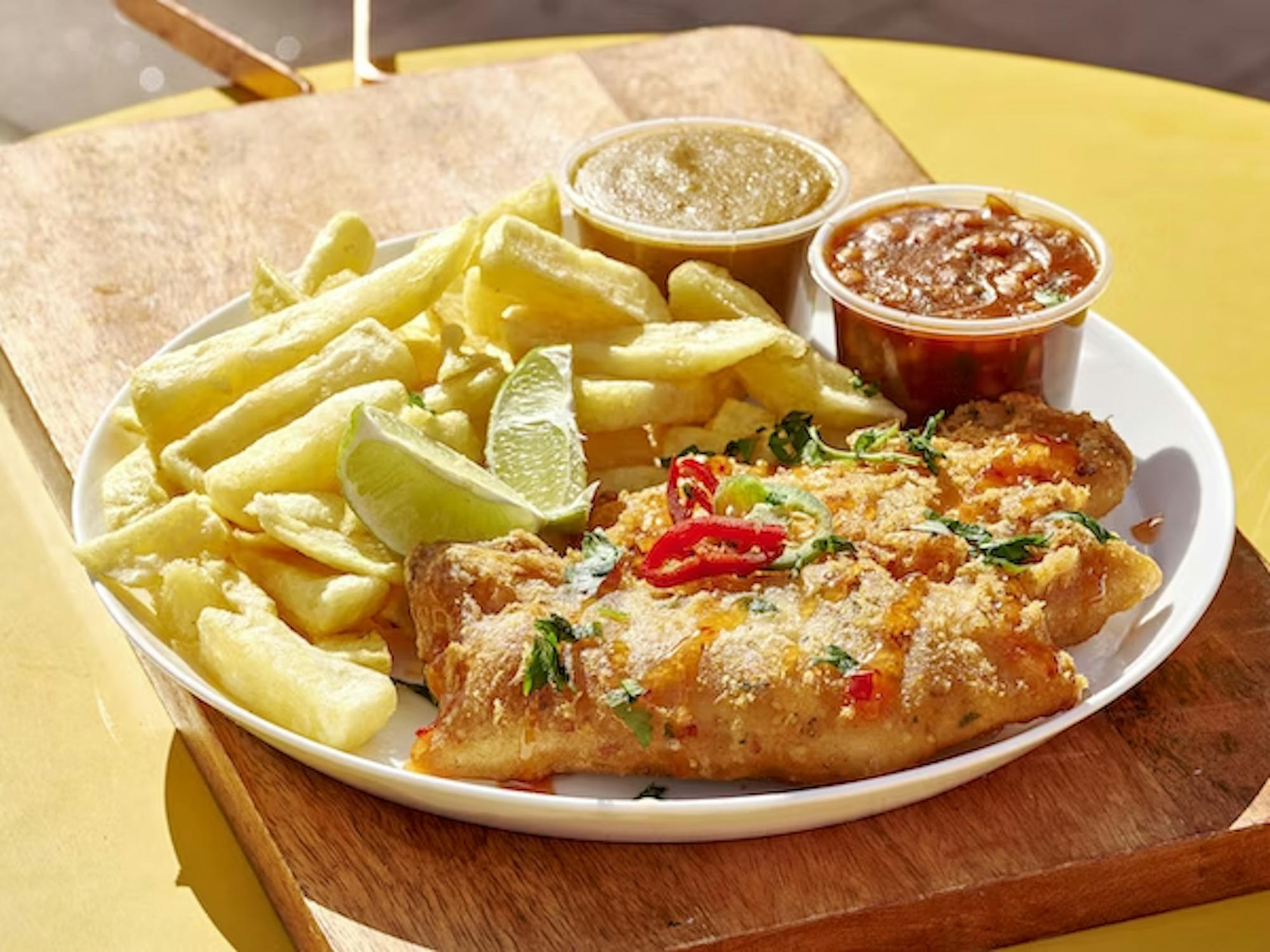 fish and chips on a plate with sauces