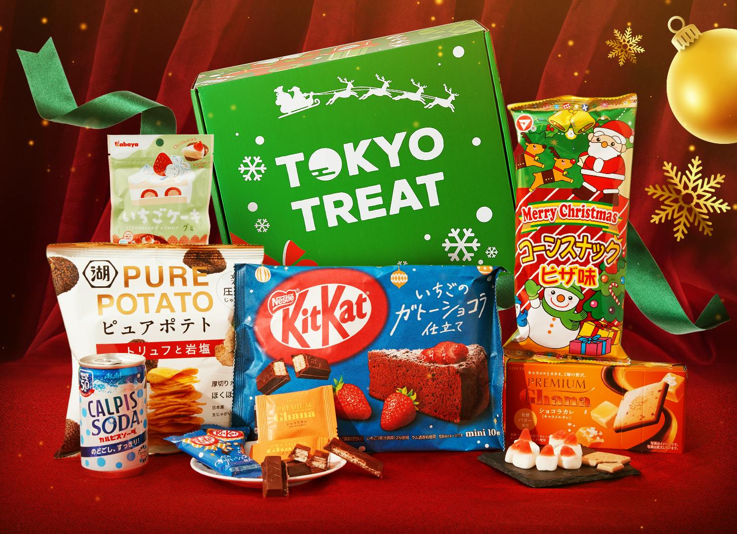 The TokyoTreat Snacktacular Christmas box sits on a dark red stage in front of red curatins, surrounding by featured items. The TokyoTreat Snacktacular Christmas box sits on a dark red stage in front of red curatins, surrounding by featured items.