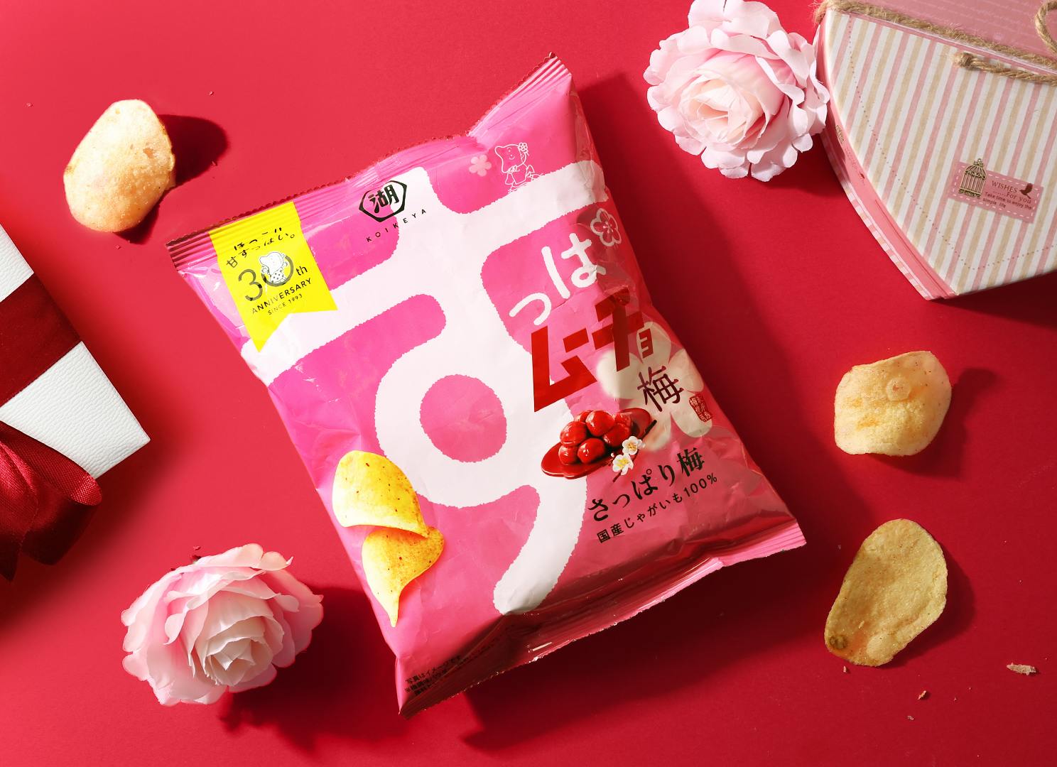 Pink Suppamucho chips are on a red table with pink flowers and Valentine's chocolates.