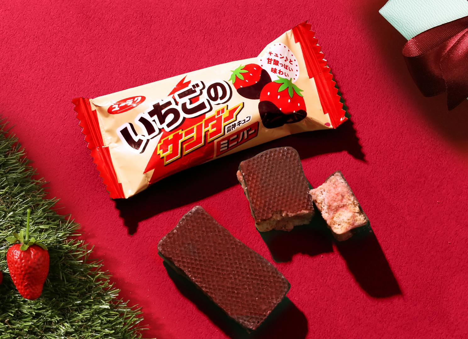 Strawberry flavored chocolate bars are on a red plate with strawberries.