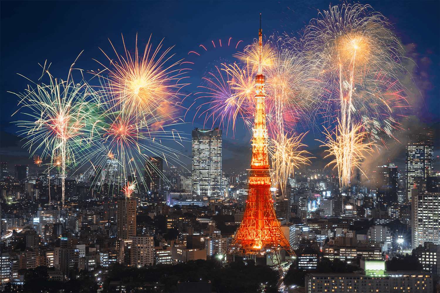 The red Tokyo Tower is pictured surrounded by skyscrapers and fireworks lighting up a night sky.
