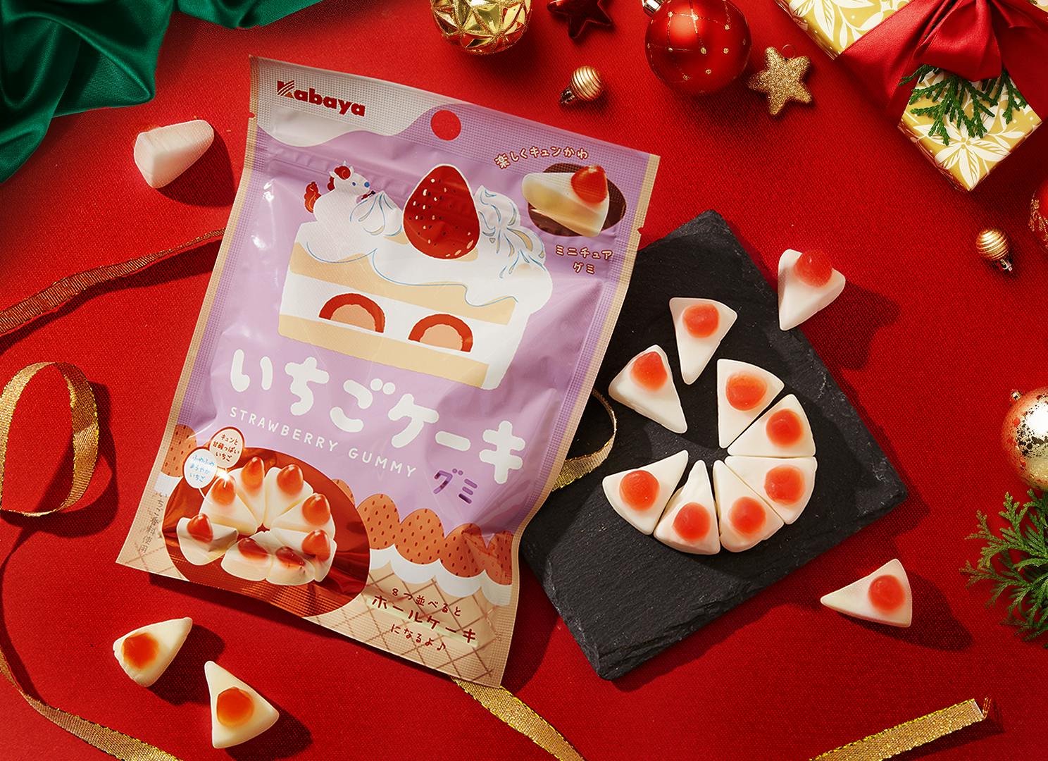 Christmas Cake Gummies sit on a table surrounded by Christmas & holiday motifs. Christmas Cake Gummies sit on a table surrounded by Christmas & holiday motifs.