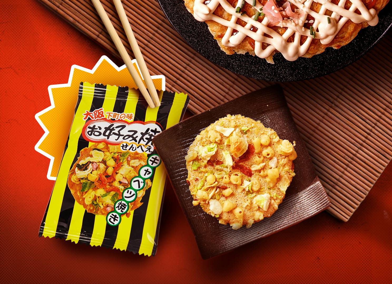 A small senbei topped with okonomiyaki toppings sits on a plate next to its yellow packaging